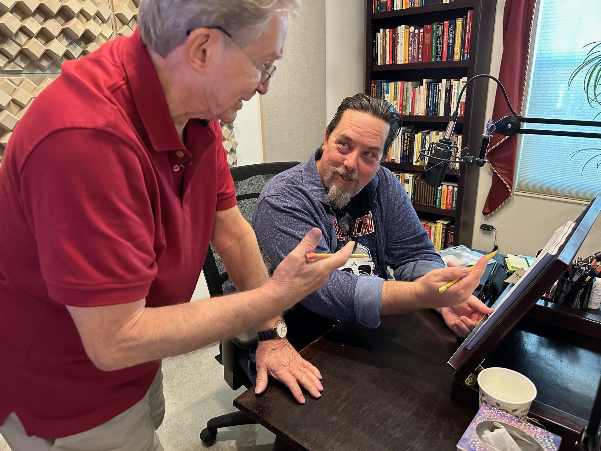 Voice acting coach reviewing a script with a student in a professional recording studio during voice-over training.